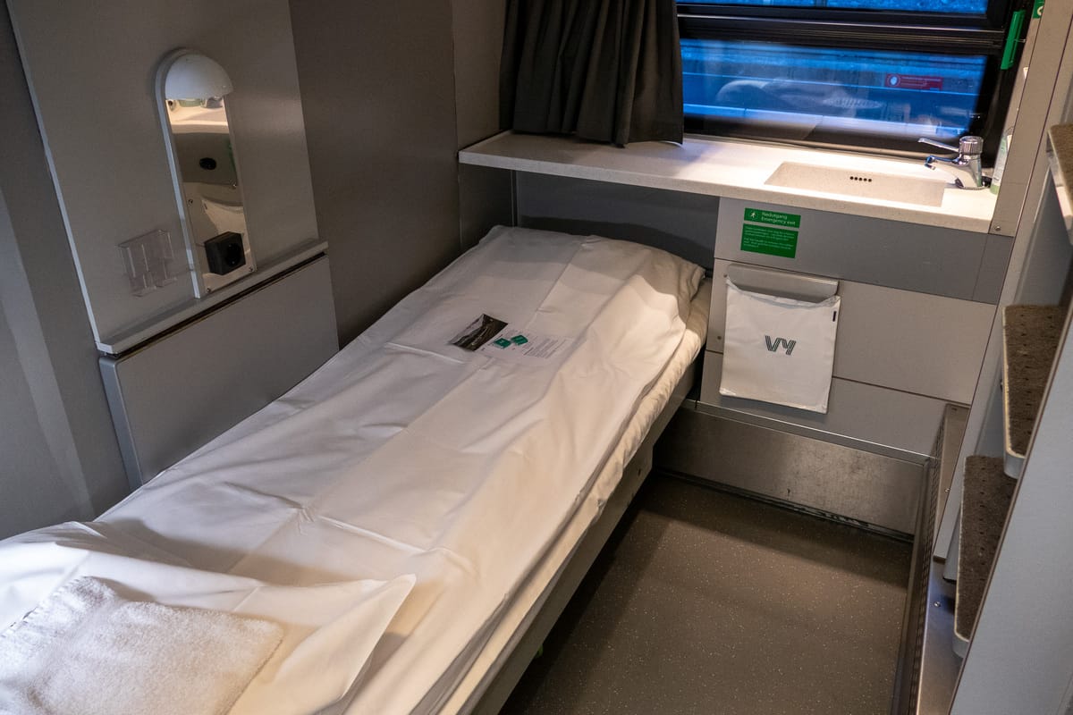 Compartiment de voiture-lit avec lit fraîchement préparé et lavabo près de la fenêtre